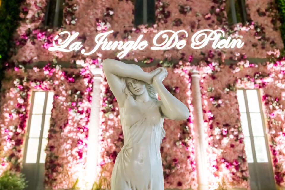 La Jungle's Garden with a statue in the center surrounded by soft lighting and pink floral decorations