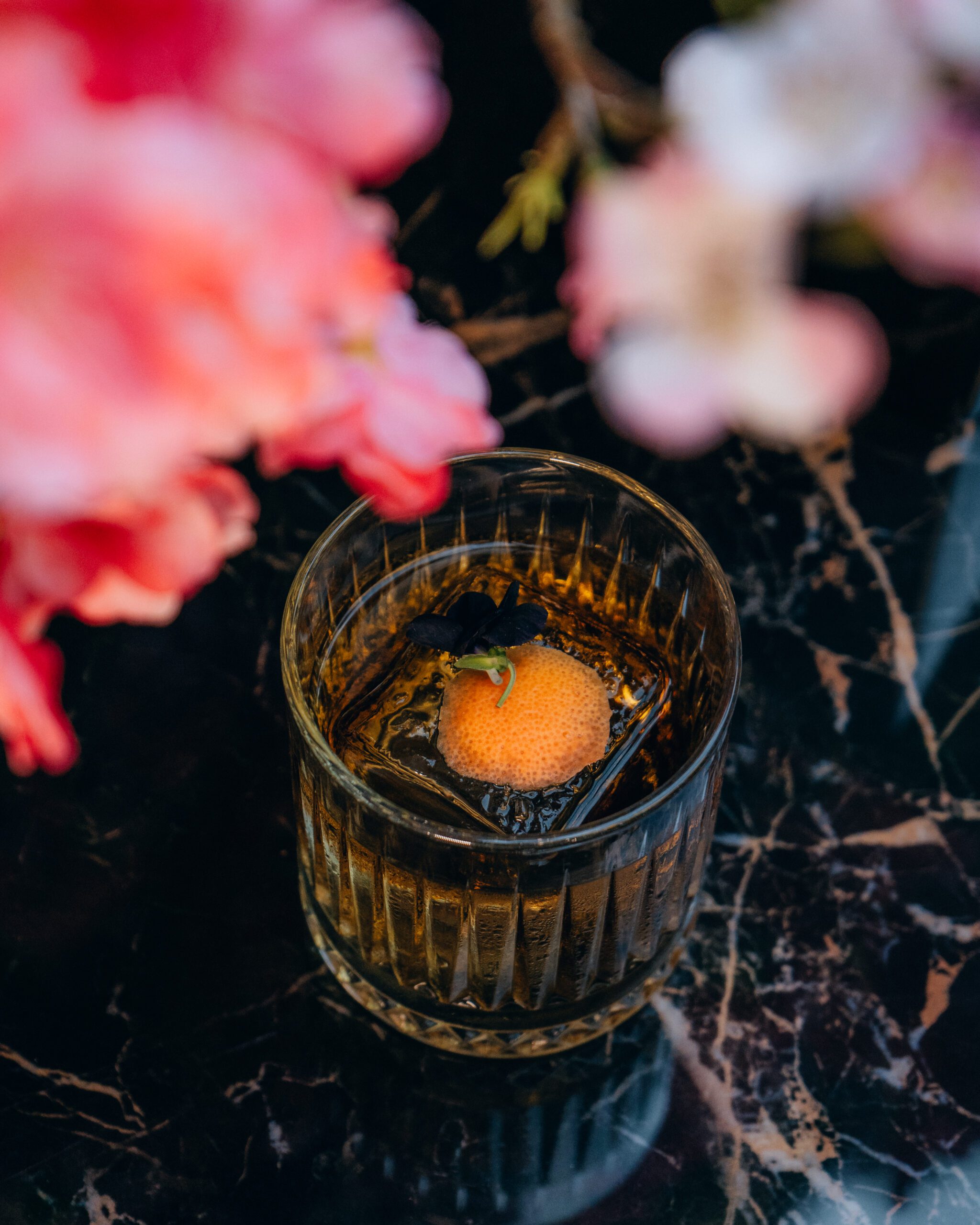 Signature cocktail with an orange slice and a square ice cube